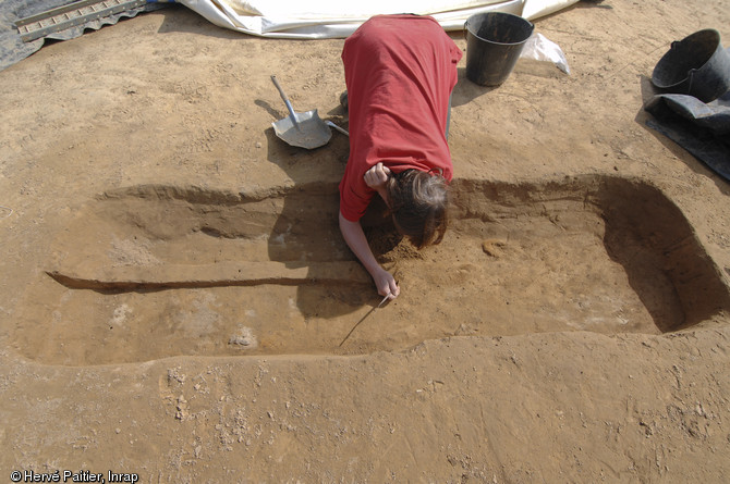 Une archéologue dégage l'une des sépultures du site.