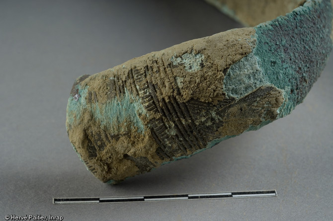 Détail d'un des sept bracelets en bronze découverts dans un vase en terre cuite à l'occasion d'un diagnostic mené à Domloup (Ille-et-Vilaine) en 2009.  Par leurs caractéristiques, les bracelets ont été rapprochés des bracelets de type  Bignan , attribués au Bronze Moyen (entre 1600 et 1200 avant notre ère). 