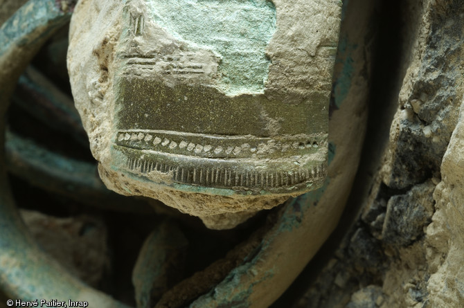 Détail de la décoration d'un des sept bracelets de bronze découverts à Domloup (Ille-et-Vilaine) à l'occasion d'un diagnostic mené en 2009.  Tous les bracelets du dépôt ont subi des déformations, que ce soit par torsion ou par écrasement. Le dépôt a été enfoui vers 1300 avant notre ère.  