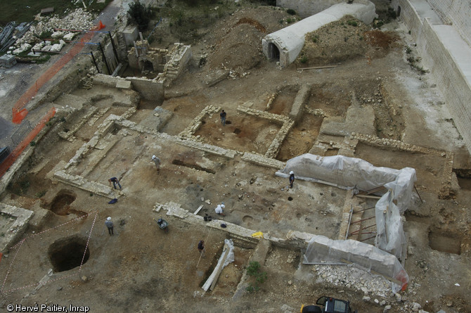 Le grand bâtiment au centre du cliché est une forge, en activité entre les XIVe et XVIe siècles. En haut à gauche de la forge on distingue une maison d'habitation datée de la même période, ayant possédée deux puis trois niveaux. Fouille du château de Caen (Calvados), 2005. 