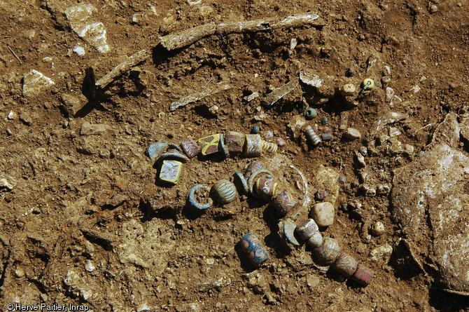 Ensemble de perles en pâte de verre formant un collier découvert sur le squelette d'un enfant, nécropole mérovingienne de Norroy-le-Veneur, VIIe-VIe s., 2005.