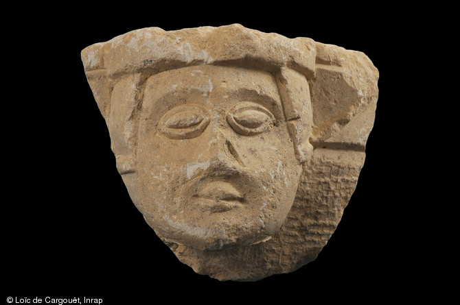 Fragment de mortier en calcaire représentant une tête humaine, fin du XIIIe s., Auxerre (Yonne), 2003.  Cette pièce a été mise au jour dans le comblement d'un escalier menant à une galerie d'extraction de calcaire réutilisée comme cave par un prieuré. 
