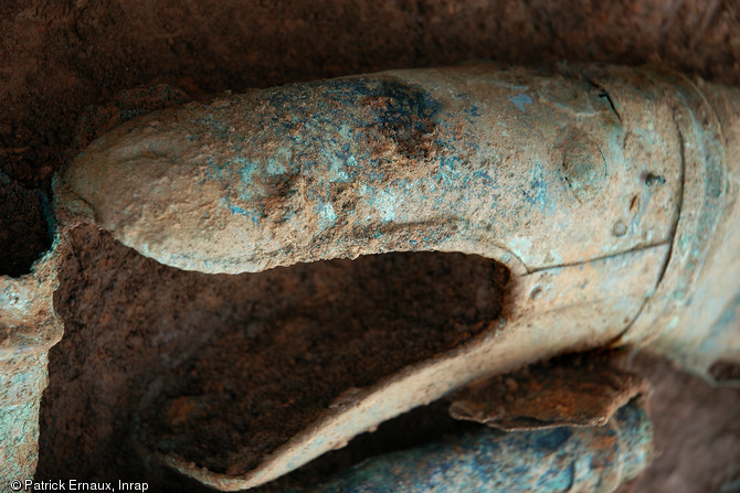 Pavillon du carnyx à tête de serpent dans la fosse dépotoir d'objets gaulois à Tintignac en Corrèze. Cette portion de trompette de guerre est constituée de tôles en alliage cuivreux, rivetées entre elles. Restauration Materia Viva