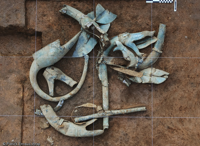 Les premiers objets déposés en fond de fosse. Le casque oiseau et cinq pavillons de trompettes de guerre ou carnyx.  Consolidation in situ, Materia Viva