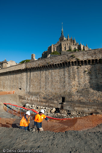 Vue de la fouille de la tour Denis au Mont-Saint-Michel (Manche) depuis le merlon protégeant le chantier des marées, 2011.  Près de 300 m3 de sable et de sédiments ont dû être déplacés afin de dégager les vestiges et de les protéger. 