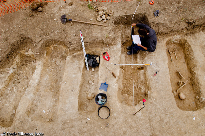 Relevé et dessin du profil du creusement d'une tombe du haut Moyen Âge, Allonnes (Eure-et-Loir), 2011.  A l'image de cette rangée de sépultures, la nécropole toute entière, utilisée entre les VIe et Xe siècles et riche de près de 3000 tombes, présente une organisation stricte en rangées. 