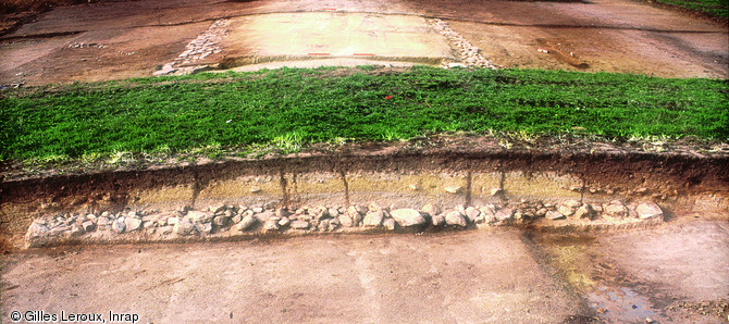 Coupe transversale de la voie antique reliant Vannes à Angers, Allaire (Morbihan), 2005.  Cette coupe indique l'existence d'un bombement épais de plus d'un mètre, constitué de recharges successives établies sur la fondation empierrée, dont la largeur atteint 7 m.     Photo publiée dans le numéro 18 de la revue de l'Inrap Archéopages.