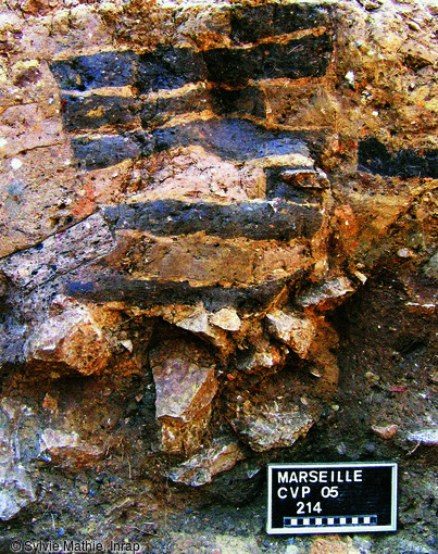 Mur en adobe (briques de terre crue) mis au jour au collège Vieux-Port à Marseille, VIe s. avant notre ère, 2005.  Les briques sont posées sur un solin de pierre et sont séparées par des joints argileux plus clairs. La fouille a permis d'étudier les premiers aménagements de la colonie grecque.