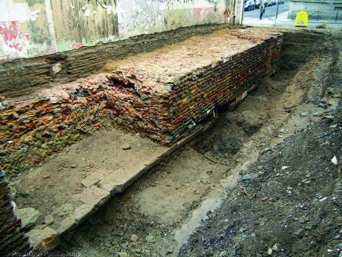 Face interne d'un tronçon de la muraille du castrum de Rennes (Ille-et-Vilaine), fin du IIIe - début du IVe s. de notre ère, 2006.  Conservé sur 3,6m de large et sur 2m de haut, le rempart est doté de fondations en grand appareil remployé parmi lesquels figurent des éléments architecturaux.    Photo publiée dans le numéro 20 de la revue de l'Inrap <a class= rte-link-ext  href= http://www.inrap.fr/archeologie-preventive/La-Recherche/Archeopages/Numeros-en-ligne/18-19-20-2007/Numero-20/Dossier-Naissance-de-la-