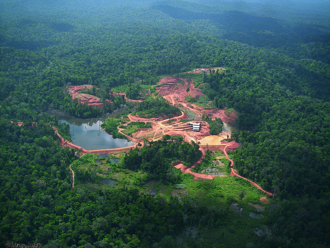 Vue aérienne du site de Yaou (Guyane), 2006.  Au premier plan apparaissent les dégradations anciennes de l'orpaillage traditionnel, qui ont modifié le tracé initial du cours d'eau. Au deuxième plan, l'exploitation actuelle du gisement aurifère qui s'attaque au relief. Au troisième plan, la base archéologique implantée sur le massif tabulaire de Yaou. A l'horizon, la zone de prospection, recouverte par la forêt tropicale.   Photo publiée dans le numéro 23 de la revue de l'Inrap <a class= rte-link-ext  href= http://www.inrap.fr/archeologie-preventive/Recherche-scientifique/Archeopage