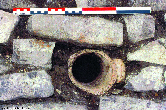 Détail de l'embouchure d'une des amphores intégrée à la maçonnerie du bassin d'un jardin d'agrément de la villa de Peltre (Moselle), 2004.  Ces amphores jouent le rôle de niches à poisson. Elles proviennent d'Espagne et de Méditerranée orientale et ont été mises en place lors de la construction du cuvelage du bassin, disposés à plat dans le substrat à l'arrière du parement.  Photo publiée dans le numéro 29 de la revue de l'Inrap <a class= rte-link-ext  href= http://www.inrap.fr/archeologie-preventive/Recherche-scientifique/Archeopages/Les