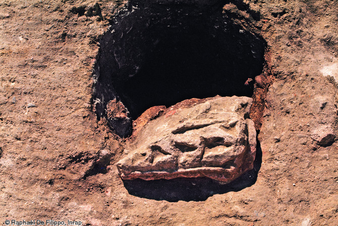 Fragment d'un chapiteau Ionique antique utilisé comme calage d'un poteau médiéval, à l'emplacement du temple du forum place Esquirol (Toulouse), 2004-2005.  Photo publiée dans le numéro 29 de la revue de l'Inrap Archéopages.
