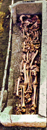 Sépulture en sarcophage attestant de la pratique de la réduction repoussée, nécropole du haut Moyen Âge de Chadenac (Charente-Maritime), 1995.  Les ossements du premier occupant du sarcophage ont été repoussés vers la paroi sud (à gauche sur la photo). Par la suite, deux autres individus y ont été successivement déposés.  Photo publiée dans le numéro 29 de la revue de l'Inrap <a class= rte-link-ext  href= http://www.inrap.fr/archeologie-preventive/Recherche-scientifique/Archeopages/Les-numeros/28-29-30-HS02-2010/Numero-29/Dossier-Recyclage-et-remploi/p-11773-Reutilisation-de-tom