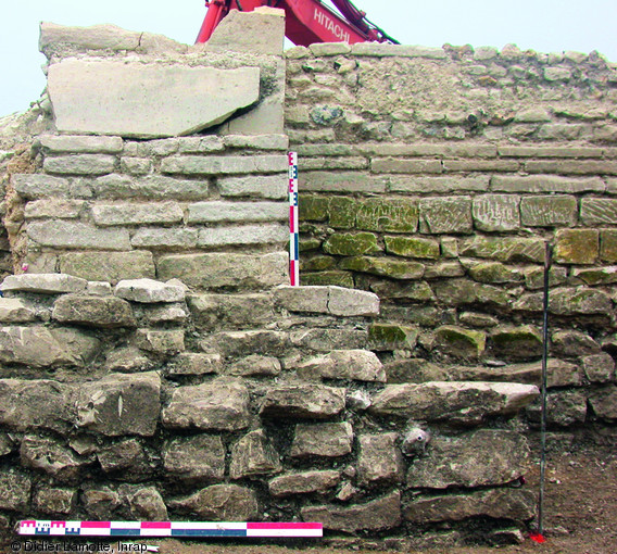 Mur et contrefort de la tour de l'église Notre-Dame-aux-Nonnains, première moitié du XIe s., Troyes (Aube), 2004-2008.  A la base de l'élévation du contrefort, on observe plusieurs assises de moellons de craie. Au deuxième plan, les assises sont constituées par des plaquettes débitées dans des sarcophages probablement antiques. Ces derniers ont été découpés afin de conserver au moins un angle de la cuve, créant ainsi un pseudo-grand appareil.   Photo publiée dans le numéro 29 de la revue de l'Inrap <a class= rte-link-ext  href= http://www.inrap.fr/archeologie-preventive/