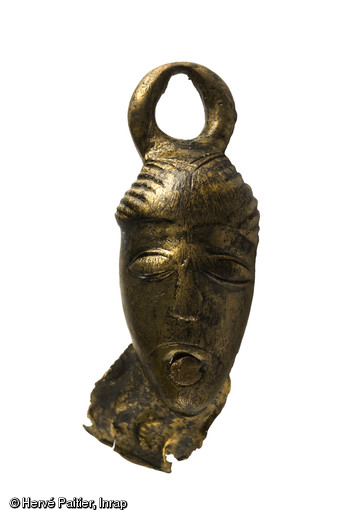 Attache d'anse de seau anthropomorphe en bronze, daté du Ier s. avant notre ère, découvert à Orval (Manche) dans un puits de la fin du Ier s. avant notre ère. (Hauteur : 5,5 cm, longueur max: 2,2 cm). Découverte durant l'été 2006, la tombe d'Orval est aujourd'hui un cas unique : la plus occidentale des « tombes à char » de la fin de La Tène ancienne jamais trouvée en Europe.