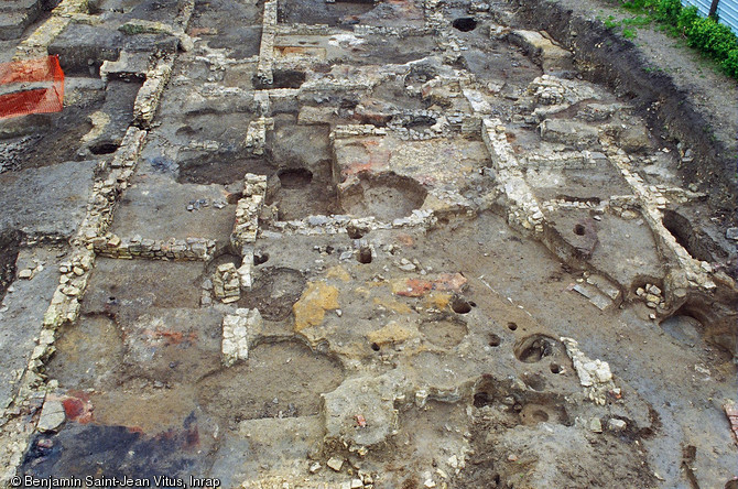 Détail en fin de fouille du grand bâtiment allongé du IXe s. au sommet d'un talus parallèle à la Loire, en bordure du domaine de l'abbaye Saint-Genès et Notre-Dame à Nevers (Nièvre), 2004.L'édifice correspondrait au palais des hôtes de marque du monastère. Au premier plan des vestiges de sols criblés de fosses-silos et de trous de poteaux des occupations ultérieures (Xe-XIIe s.). Au second plan apparaissent des aménagements de jardins (rigoles, citernes...) des XVIIe et XVIIIe s.