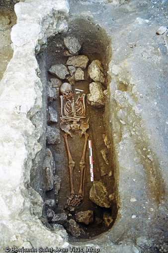 Détail d'une inhumation privilégiée prenant place dans une pièce particulière du grand bâtiment du IXe s., interprété comme le palais des hôtes de l'abbaye Saint-Genès et Notre-Dame de Nevers (Nièvre), 2004.Mordant sur l'épaisseur d'un mur intérieur, la sépulture est installée dans un  en-feu , une sorte de niche généralement surmontée d'un arc mettant en valeur la sépulture.