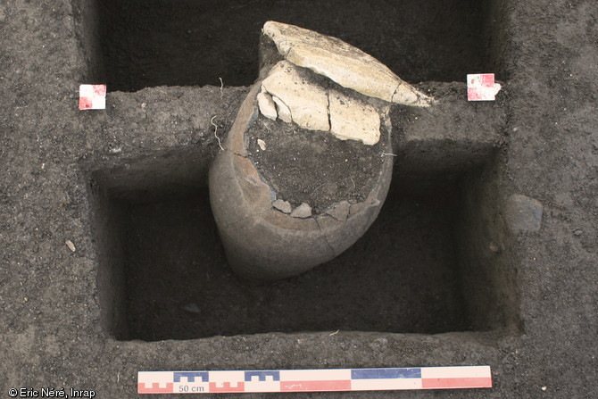 Vase entier du Bronze moyen (1600-1500 avant notre ère) sur le site des Queyriaux à Cournon-d'Auvergne (Puy-de-Dôme), 2011.  Le vase a été installé au fond d’une fosse, son ouverture correspondant au niveau du sol. Une plaquette de marno-calcaire a été taillée pour le boucher. Cette roche claire pourrait également signaler la présence du vase enterré.