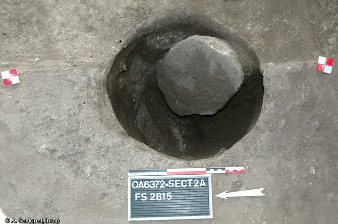 Trou de poteau chasséen du site des Queyriaux à Cournon-d'Auvergne (Puy-de-Dôme), 2011.  Une meule est réutilisée pour caler le poteau dans la fosse d’implantation.