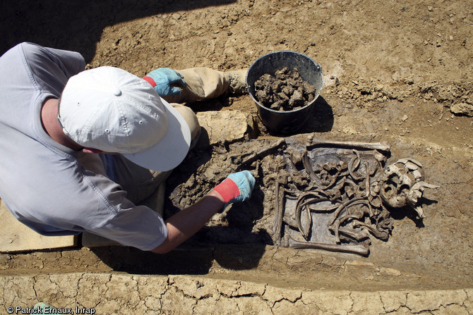 Sépulture médiévale en cours de fouille à Marsan (Gers) en 2008.  Des restes de matière organique (en gris) et des anomalies taphonomiques majeures (os en désordre) sont observables. 