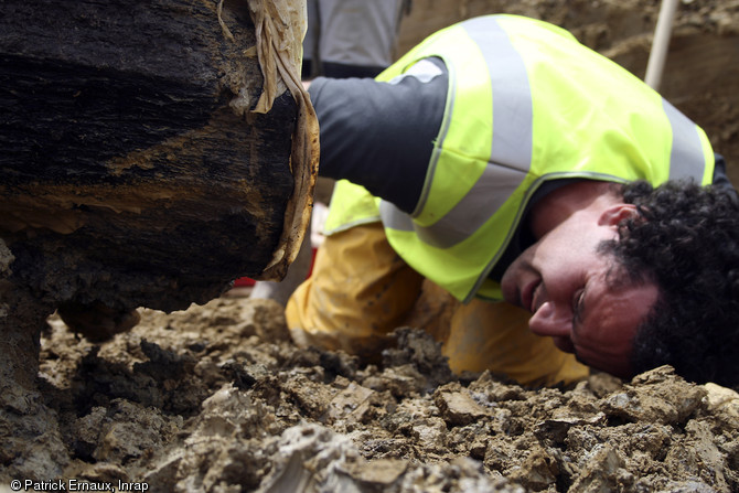 Observations en vue de l'élaboration du coffrage pour le prélèvement du cercueil monoxyle, cimetière médiéval de Marsan (Gers), 2008.  Le prélèvement intégral du cercueil constituait le meilleur moyen de le conserver. Un coffrage adapté a donc du être imaginé. 