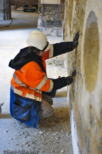 Enlèvement des enduits récents sur un des murs du couvent des Jacobins à Rennes (Ille-et-Vilaine), 2012.  Cette opération permet de révéler les anciennes maçonneries de l'édifice dans le cadre de l'étude du bâti. 