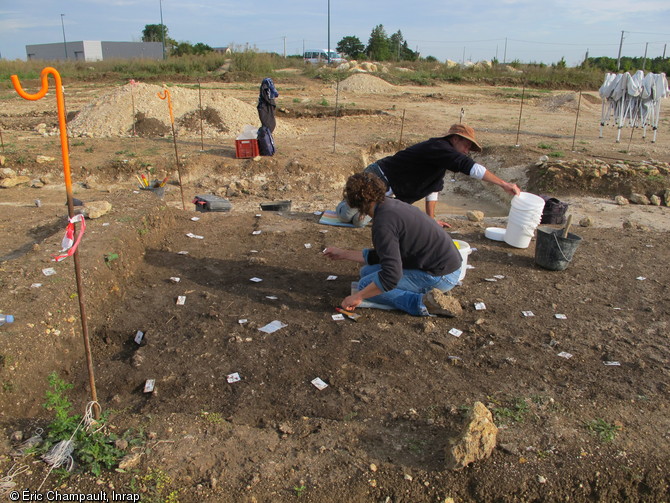 Fouille de la couche de rejet de bûcher, Épieds-en-Beauce (Loiret), 2010.  Le carroyage est matérialisé au sol  par les étiquettes afin de ne pas gêner la fouille. Des prélèvements sont systématiquement réalisés dans chaque carré afin de recueillir ossements, céramiques, éléments métalliques et tout autre indice de toute petite taille.