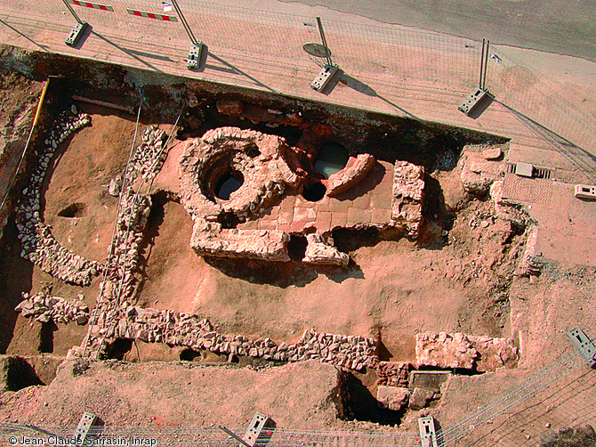 Baptistère mis au jour en 2005 à Roanne (Loire) dans une pièce dallée d'une maison du IIIe s.  Ce premier emplacement se révèle rapidement trop petit. Un baptistère plus grand est alors reconstruit au-dessus du précédent. La superficie de la pièce, quasiment doublée, atteint 30 m2 et une abside semi-circulaire est ajoutée à l'est (à gauche de la photo).  Photo publiée dans l'ouvrage Archéologie médiévale en France - Le premier Moyen Âge, Isabelle Catteddu, coll. Archéologies de la France. 