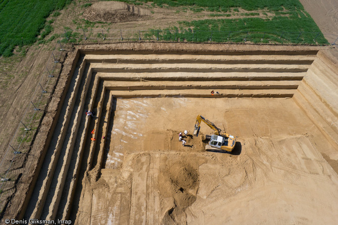 Décapage à la pelle mécanique, Havrincourt (Nord-Pas-de-Calais), 2011.Afin d'atteindre les niveaux d'occupations préhistoriques, il a fallu décaper jusqu'à 4500 m2 de terre sur 6 m de profondeur.   Photo publiée dans l'ouvrage La France racontée par les archéologues, par C. Marcigny et D. Bétard, coédition Gallimard - Inrap. 