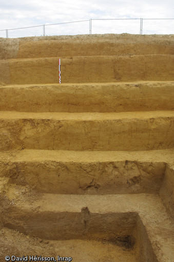 Vue des six premiers mètres de sédiment au nord du gisement. Au premier plan apparaissent les sols humifères gris du niveau acheuléen datant d'un peu plus de 300 000 ans, Étricourt-Manancourt (Somme), 2012.  Les silex taillés appartenant à ce niveau ont été façonnés soit par les derniers Homo Heidelbergensis soit par les premiers Néandertaliens. 