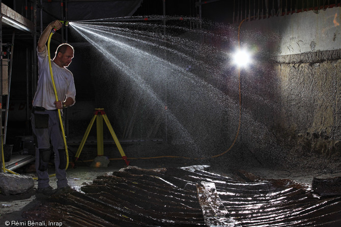 Arrosage nocturne du bateau, port antique d'Antibes (Alpes-Maritimes), 2012.Les bois archéologiques, gorgés d'eau, doivent être arrosés régulièrement pour être préservés. Ensuite, ils seront traités en laboratoire où l'eau sera progressivement remplacée par une résine de consolidation.