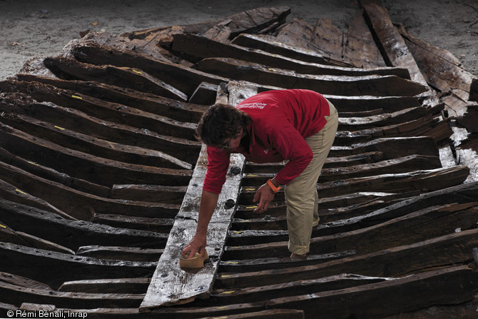 Nettoyage de l'épave romaine mise au jour dans le port antique d'Antibes (Alpes-Maritimes) en 2012.Le bois utilisé dans la construction du navire est de qualité moyenne : la coque est par endroits renforcée par des plaquettes de plomb maintenues par de petits clous.