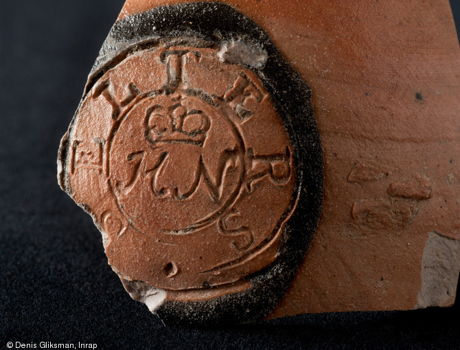 Détail du cachet apposé sur une bouteille en grès produite dans le Westerwald (Rhénanie-Palatinat) au XVIIIe ou au XIXe s., découverte place du Château à Strasbourg (Bas-Rhin), 2012.  Dans le  cercle peuvent se lire les inscriptions suivantes :  SELTERS , et sous la couronne  HN , pour Herzogthum Nassau, un ancien État de la Confédération germanique. 