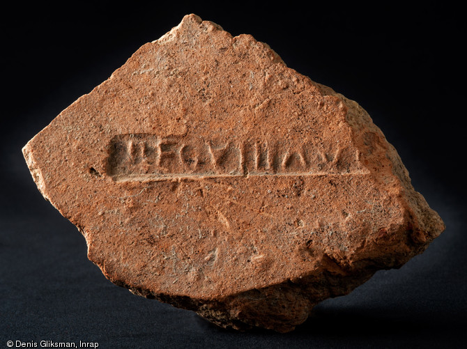 Fragment d'une tuile ou d'une brique romaine marquée par l'estampille de la VIIIe légion Auguste ( LEG VIII AUG ), place du Château, Strasbourg (Bas-Rhin), 2012.  La légion s'installe dans l'antique Argentorate dans les années 90 de notre ère. Ses 6000 hommes y érigent un camp fixe de près de 20 ha qui formera ensuite le cœur de la cité épiscopale, aujourd'hui encore centre de la ville. 