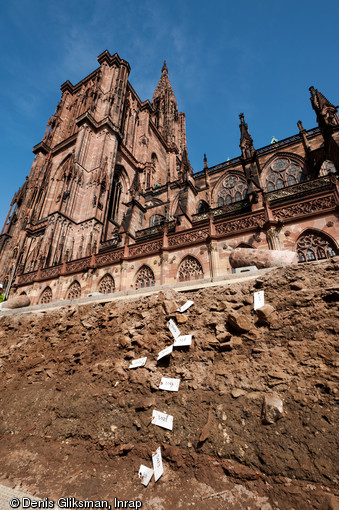 Fouille aux abords de la cathédrale de Strasbourg (Bas-Rhin), 2012.  À l'arrière plan la cathédrale ; au premier plan, les niveaux archéologiques du chantier de construction de cette dernière, édifiée entre le XIIe et le XVe s. On retrouve dans ces niveaux quantité d'éclats de grès nous renseignant sur les techniques de taille. 