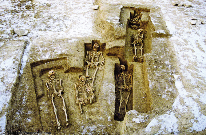 Ensemble de sépultures anthropomorphes, c'est-à-dire taillées dans le substrat pour épouser la forme générale d'un corps humain, avec encoche céphalique pour abriter la tête, début du second Moyen Âge, Châlons-en-Champagne (Marne), 1994.  Photo publiée dans l'ouvrage Archéologie de la mort en France, Lola Bonnabel, coll. Archéologies de la France. 