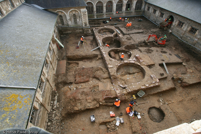 Vue générale de la fouille dans le jardin du cloître du couvent des Jacobins à Rennes (Ille-et-Vilaine), 2012.  Le décapage a entre autres révélé les fondations d'un bâtiment militaire du XXe s. comprenant les quatre imposantes cuves visibles au centre de la photo. 