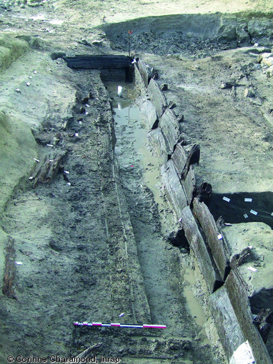 Pieux et planches de chêne soutenant des quais situés le long d'un paléochenal de la Marne, Tène finale, Chelles (Seine-et-Marne), 2007.   Photo publiée dans le numéro 23 de la revue de l'Inrap Archéopages. 