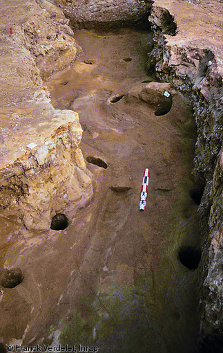 Paire d'ornières longilignes et trous de poteaux d'étayage dans une galerie de mine exploitée depuis le IVe s. avant notre ère jusqu'à la fin de l'Antiquité, La Bazoge (Sarthe), 1998.   Photo publiée dans le numéro 22 de la revue de l'Inrap <a class= rte-link-ext  href= http://www.inrap.fr/archeologie-preventive/Recherche-scientifique/Archeopages/Les-numeros/HS01-21-22-23-2008/Numero-22/Dossier-Mines-et-carrieres/p-9468-Le-minerai-de-fer-et-son-extraction-de-la-Protohistoire-au-XIXe-siecle-dans-l-ouest-de-la-France.-Presentation-des-quatre-mines-fouillees-sur-le-trace-de-l-A