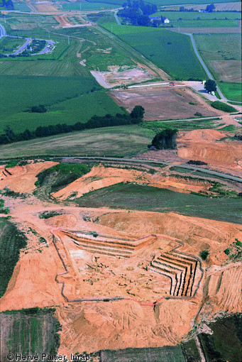 Fouille des réseaux miniers protohistoriques et antiques sur le tracé de l'A28, La Bazoge (Sarthe), 1998.  La profondeur des puits et la grande instabilité des sédiments ont conduit à fouiller à ciel ouvert avec un terrassement par paliers successifs de 1,3 m de hauteur.   Photo publiée dans le numéro 22 de la revue de l'Inrap <a class= rte-link-ext  href= http://www.inrap.fr/archeologie-preventive/Recherche-scientifique/Archeopages/Les-numeros/HS01-21-22-23-2008/Numero-22/Dossier-Mines-et-carrieres/p-9468-Le-minerai-de-fer-et-son-extraction-de-la-Protohistoire-au-XIXe-siecle-dans-