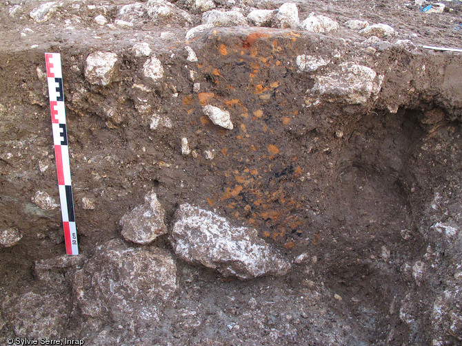 Coupe d'un trou de poteau comblé de fragments de terre cuite, 150-80 avant notre ère, Meung-sur-Loire (Loiret), 2011.Dix bâtiments construits sur poteaux ont été repérés au sein d'un grand espace enclos quadrangulaire.