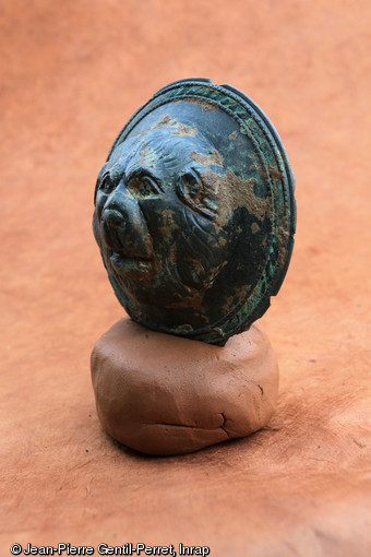Phalère à tête de lion en bronze, IVe s. de notre ère, Décines (Rhône), 2011.Cette petite parure circulaire a été mise au jour dans un des nombreux dépôts votifs disséminés autour du fanum.