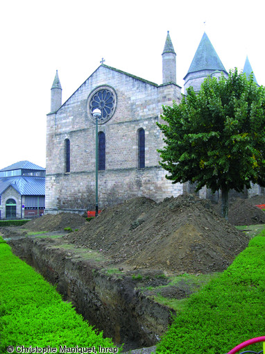 Tranchées de sondages creusées dans le jardin de la place Lénine à Saint-Junien (Haute-Vienne), 2009.L'opération a pour but de délimiter l'ampleur des cimetières anciens attenants à la Collégiale, à la fois en surface et en profondeur.