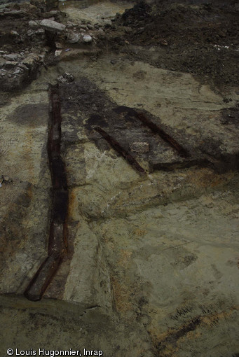 Caniveau couvert en bois associé à une vanne, bas Moyen Âge, ferme à cense de Couloisy (Oise), 2010.  Un système complexe de drainage associé à un bassin octogonal, dont la fonction reste énigmatique, a été mis au jour. 