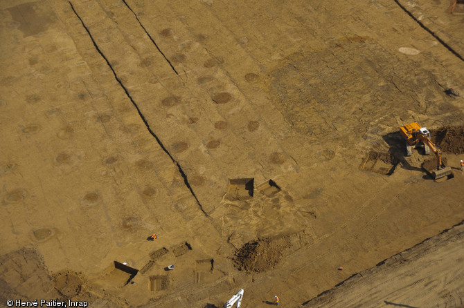 Vue aérienne de la mine des Rochardières à La Milesse (Sarthe), 2012.Les taches circulaires sombres matérialisent l'entrée des puits. Près de 1000 fosses de ce type ont été dégagées.