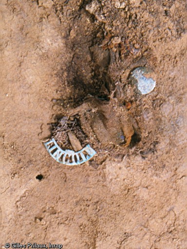 Détail de l'un des badges d'épaule  LINCOLN  retrouvés lors de la fouille de la tombe dite des  Grimsby Chums  au nord-est d'Arras (Pas-de-Calais) en 2002.Les hommes du 10e bataillon du Lincolnshire Regiment se surnommaient les  Grimsby Chums , littéralement les  potes de Grimsby , petit port du nord-est de l'Angleterre.     Photo publiée dans l'ouvrage L'archéologie de la Grande Guerre, Y. Desfossés, A. Jacques et G. Prilaux, coll. Fouilles et découvertes. 