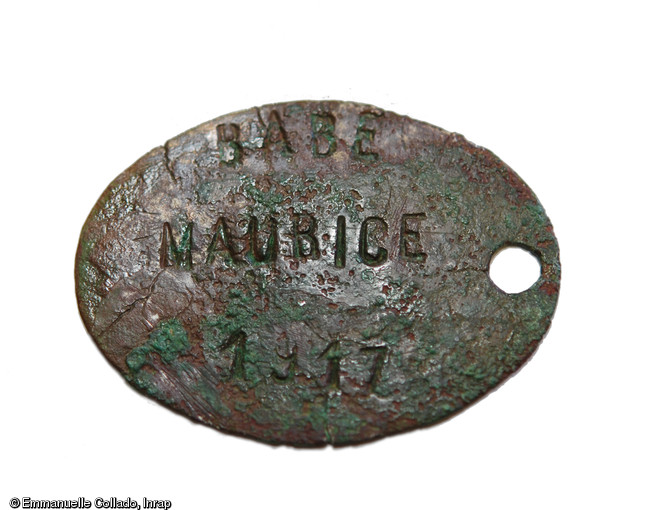 Avers de la plaque d'identité du soldat Babé portant l'inscription  Babé Maurice 1917 .Cet élément a permis l'identification précise de ce combattant  tué à l'ennemi  le 30 août 1918 dont le corps n'avait jamais été retrouvé. Sa découverte fortuite a été faite à l'occasion de la fouille d'une ferme gauloise à Campagne (Oise) en mai 2012. 