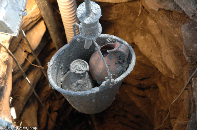 Extraction du mobilier présent au fond du puits à l'aide d'un treuil, Magalas (Hérault), 2013. Des cruches en céramique intactes, datées entre la seconde moitié du IIe et le IIIe s. de notre ère, ont été mises au jour.