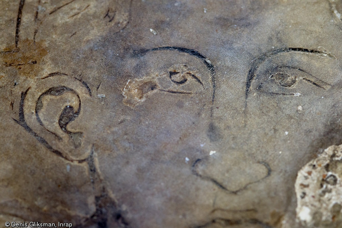 Détail d'un visage masculin sur une pierre tombale du XIVe s. remployée dans un sol d'époque moderne, église Saint-Pierre et Saint-Paul à Gonesse (Val-d'Oise), 2013.