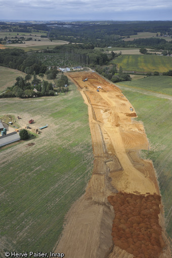 Vue aérienne des fouilles menées à La Milesse (Sarthe), 2011.Une fouille commence par le décapage à la pelle mécanique de la première couche de terre, dite végétale. Ici, les archéologues viennent d’achever le décapage.